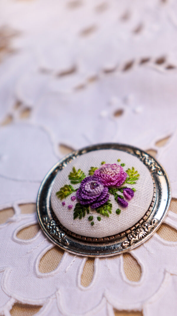 broche floral bordado em tons de roxo e rosa